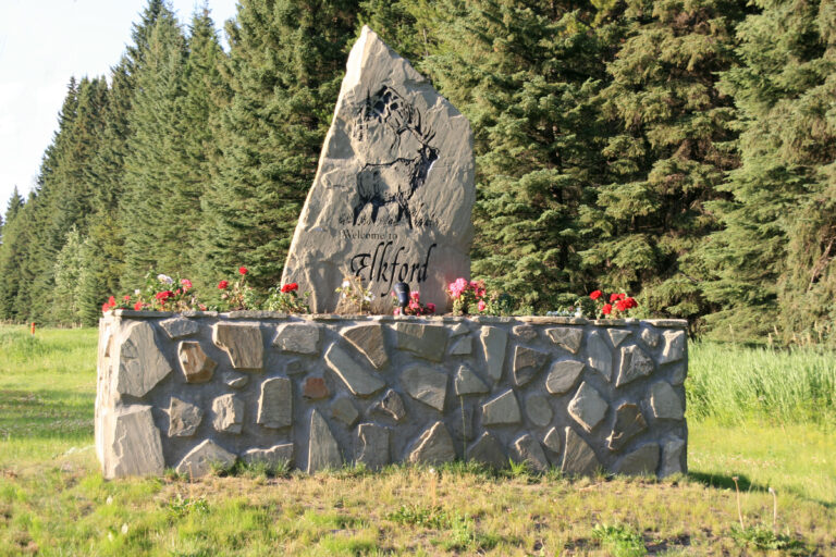 The welcome to Elkford sign, made form rock with a flower display infront